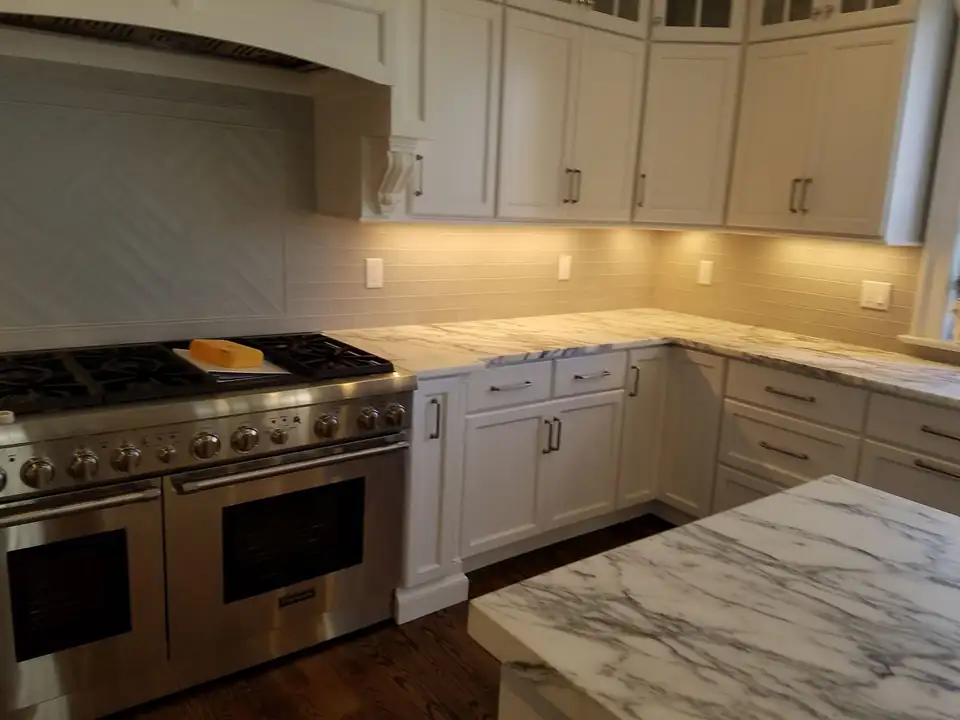 Kitchen countertops by Dunellen, NJ fabricator Lk Kitchen: white marble-look counters and island on white shaker cabinets beside a stainless pro range